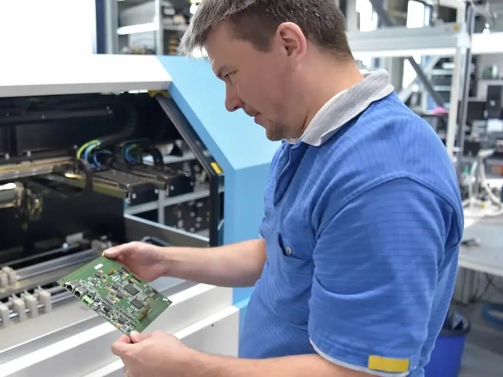 Ein Arbeiter inspiziert eine fertig montierte PCBA-Platine für Unterhaltungselektronik
