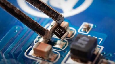 Unas pinzas recogen una resistencia SMD de la placa de circuito impreso